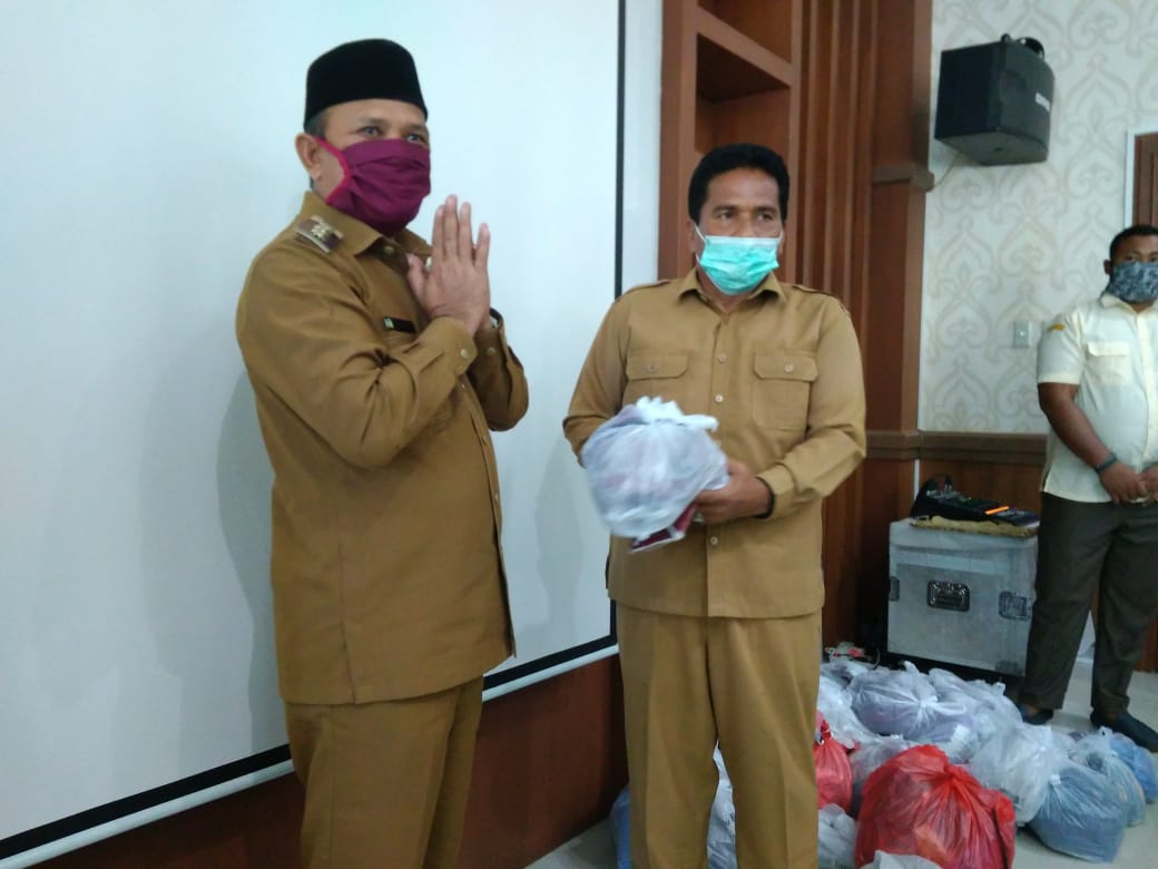 SERAHKAN MASKER - Bupati Aceh Besar Ir H Mawardi Ali secara simbolis menyerahkan bantuan masker kepada Kadis Pangan Aceh Besar Ir Fuadi Akhmad di Aula Setdakab Aceh Besar, Senin (6/4/2020). FOTO/ HUMAS PEMKAB ACEH BESAR