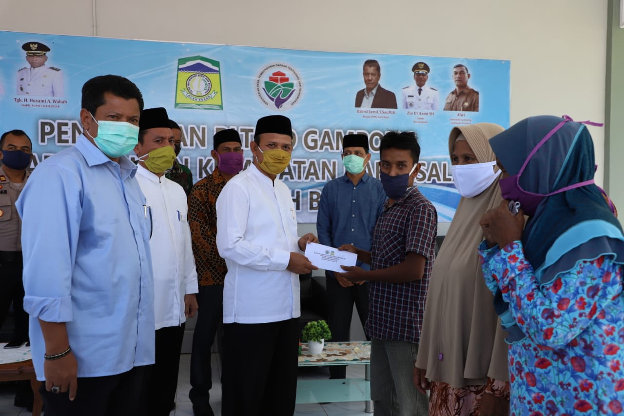 FOTO/ HUMAS PEMKAB ACEH BESAR Bupati Aceh Besar Ir H Mawardi Ali didampingi Kadis DPMG Bahrul Jamil SSos MSi secara simbolis menyerahkan BLT DD di kompleks Meunasah Gampong Lambada Peukan, Kecamatan Darussalam, Jumat (15/5/2020).